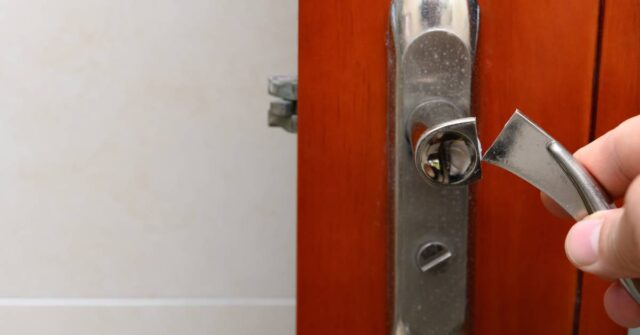 A hand holding a broken door handle.