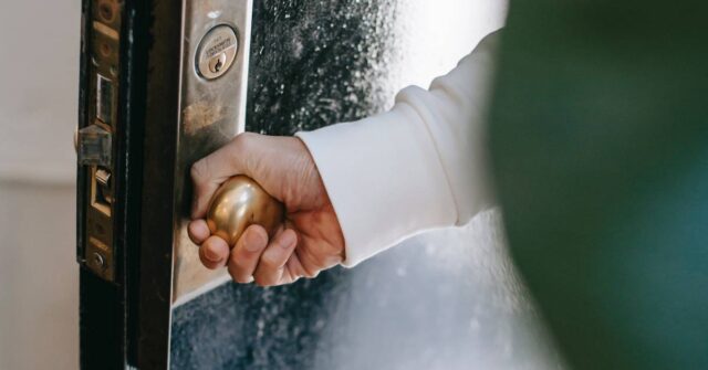 A man holding an old door knob while entering a home.