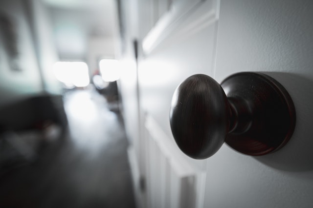 A black and white image of a door knob in a wooden door.