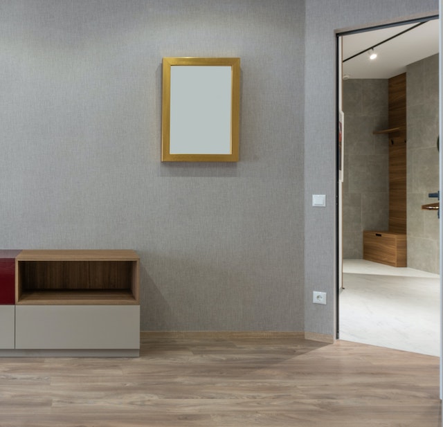 An empty house with grey walls and brown flooring.