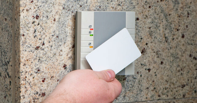 Person holding a key card up to a sensor to unlock a door and gain access.