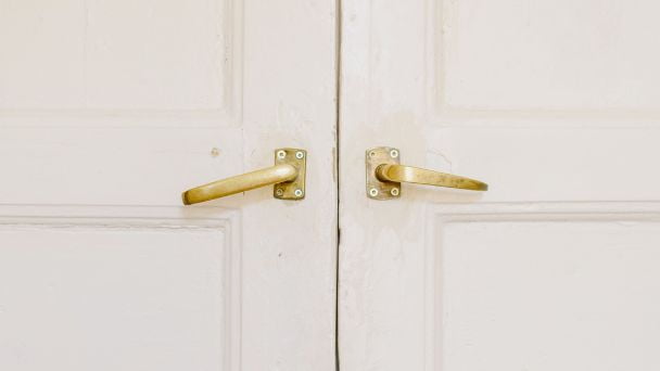 A white double door with gold lever handles.