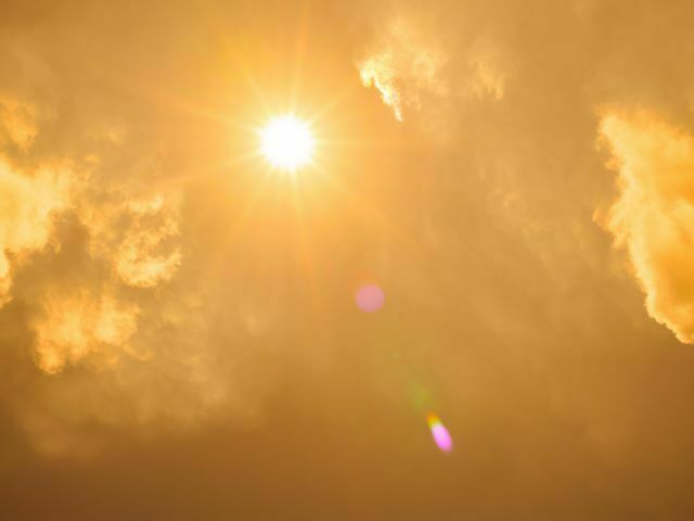 Orange sky with hot sun with few clouds.