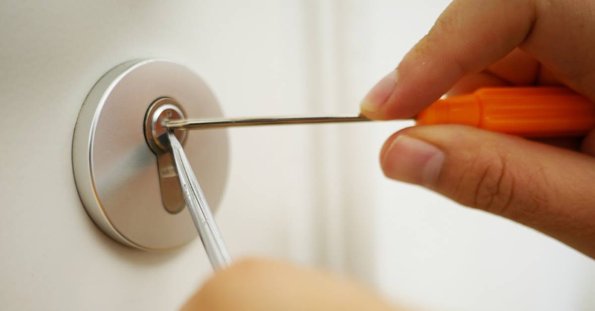 A locksmith repairing a door lock using tools.