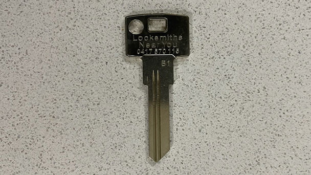 A blank restricted key with Locksmiths Near You printed on the key face.